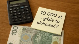 Banknot 100 zł, kalkulator i karteczka z napisem „10 000 zł – gdzie to ulokować?” na drewnianym biurku – symbol decyzji inwestycyjnej